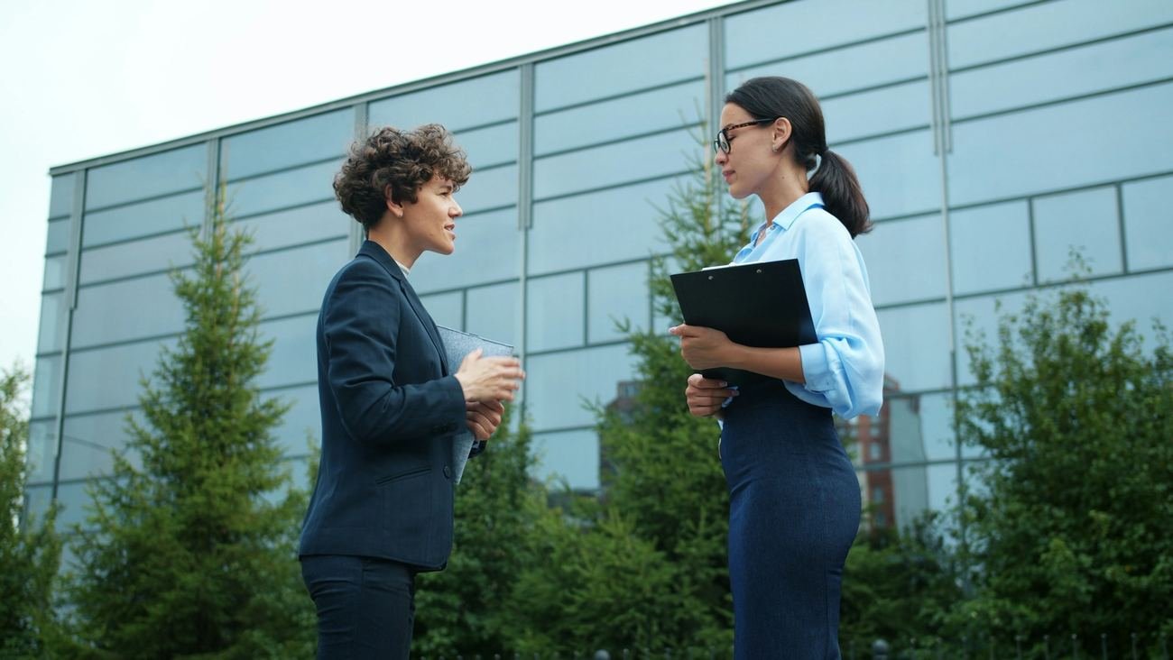 Two colleagues reviewing notes outside a building