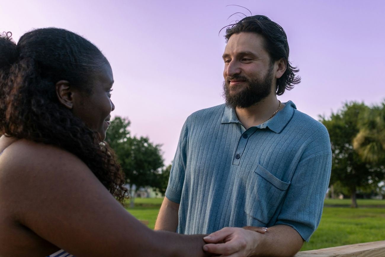 A man and a woman in easy conversation outdoors at dusk